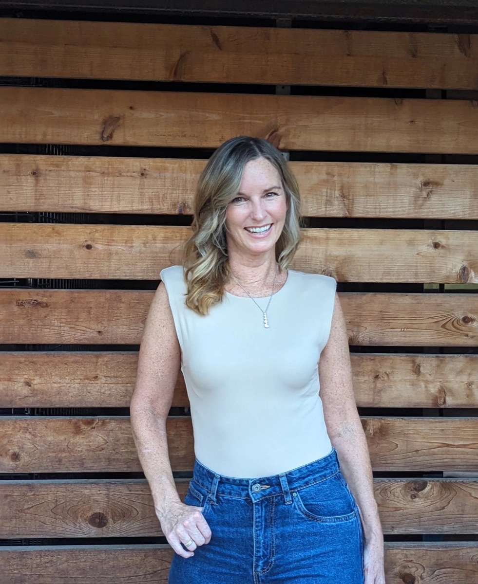 Heather MacLaren smiling in front of a warm wooden wall
