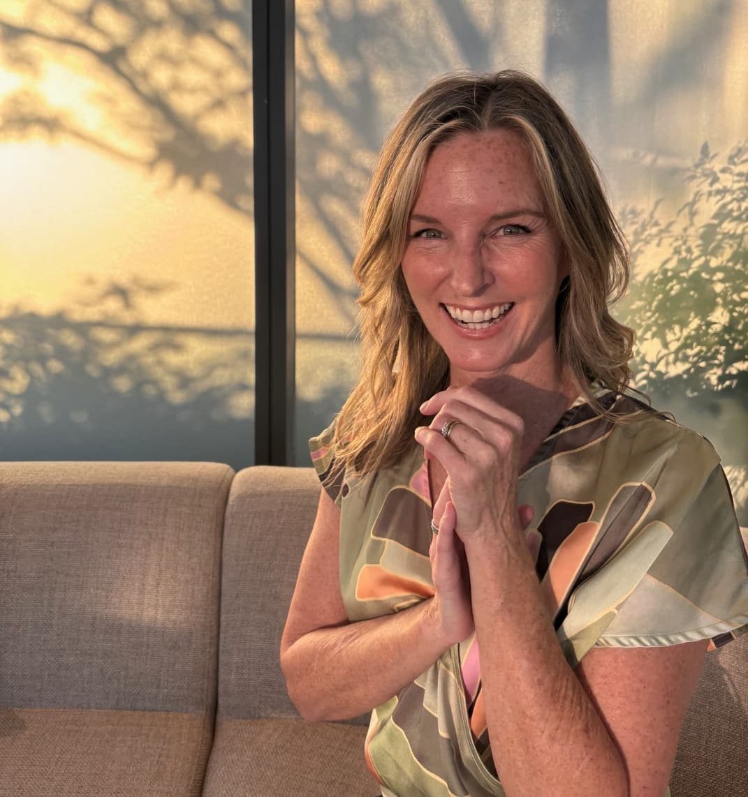 Heather MacLaren smiling to camera in golden evening light, hands clasped